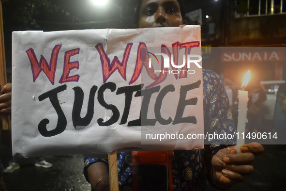 A woman is holding a placard and candle while protesting over the sexual assault and murder of a Kolkata woman doctor in Kolkata, India, on...