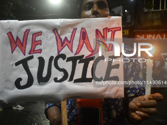 A woman is holding a placard and candle while protesting over the sexual assault and murder of a Kolkata woman doctor in Kolkata, India, on...