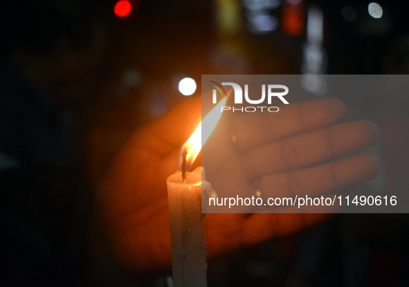 A woman is protecting a candle while protesting over the sexual assault and murder of a Kolkata woman doctor in Kolkata, India, on August 18...