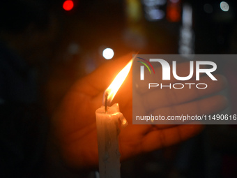 A woman is protecting a candle while protesting over the sexual assault and murder of a Kolkata woman doctor in Kolkata, India, on August 18...