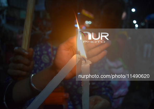 A woman is protecting a candle while protesting over the sexual assault and murder of a Kolkata woman doctor in Kolkata, India, on August 18...