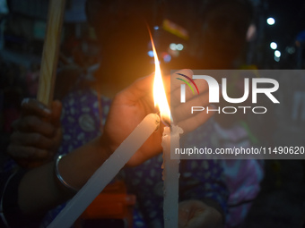 A woman is protecting a candle while protesting over the sexual assault and murder of a Kolkata woman doctor in Kolkata, India, on August 18...