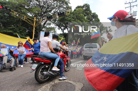 Several activists are holding banners and Venezuelan flags while gathering at a rally in Los Mangos square in San Cristobal, Venezuela, on A...