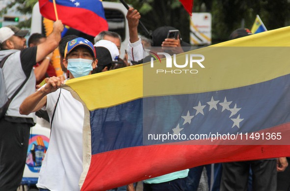 An activist is wearing a protective mask and is holding a Venezuelan flag during a rally in Los Mangos square in San Cristobal, Venezuela, o...