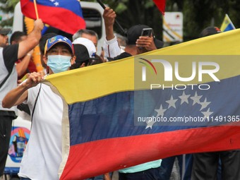 An activist is wearing a protective mask and is holding a Venezuelan flag during a rally in Los Mangos square in San Cristobal, Venezuela, o...