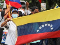 An activist is wearing a protective mask and is holding a Venezuelan flag during a rally in Los Mangos square in San Cristobal, Venezuela, o...