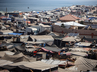 Displaced Palestinians, who are fleeing their house due to Israeli strikes, are sheltering at a tent camp amid the ongoing conflict between...