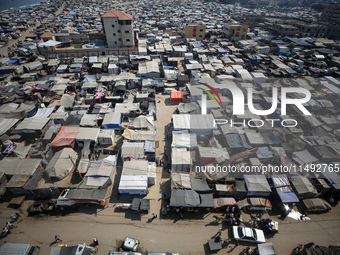 Displaced Palestinians, who are fleeing their house due to Israeli strikes, are sheltering at a tent camp amid the ongoing conflict between...