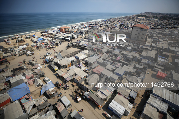 Displaced Palestinians, who are fleeing their house due to Israeli strikes, are sheltering at a tent camp amid the ongoing conflict between...