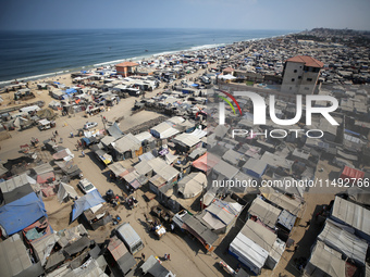 Displaced Palestinians, who are fleeing their house due to Israeli strikes, are sheltering at a tent camp amid the ongoing conflict between...