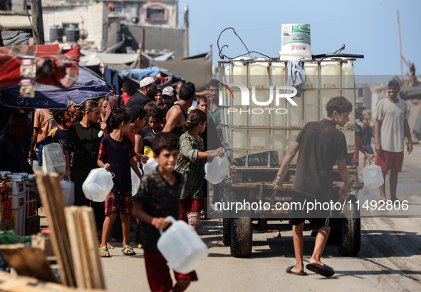 Palestinian displaced people are trying to fill containers with water in Deir el-Balah, Gaza Strip, on August 19, 2024, amid the ongoing con...