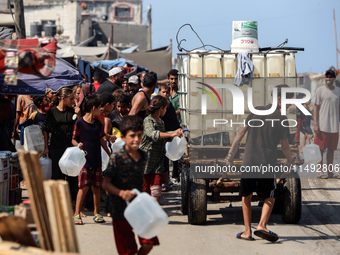 Palestinian displaced people are trying to fill containers with water in Deir el-Balah, Gaza Strip, on August 19, 2024, amid the ongoing con...