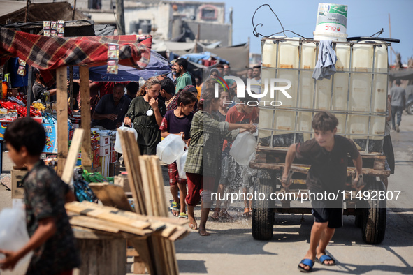 Palestinian displaced people are trying to fill containers with water in Deir el-Balah, Gaza Strip, on August 19, 2024, amid the ongoing con...