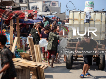 Palestinian displaced people are trying to fill containers with water in Deir el-Balah, Gaza Strip, on August 19, 2024, amid the ongoing con...