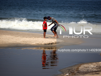 Palestinian displaced people are crossing a beach flooded with sewage water next to their tents in Deir al-Balah in central Gaza Strip, on A...