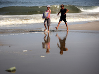 Palestinian displaced people are crossing a beach flooded with sewage water next to their tents in Deir al-Balah in central Gaza Strip, on A...