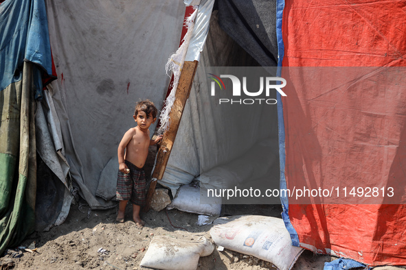 A displaced Palestinian child is standing in front of his family's tent near the beach in Deir al-Balah in the central Gaza Strip, on August...