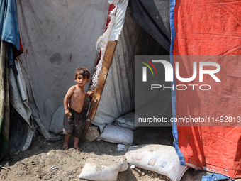 A displaced Palestinian child is standing in front of his family's tent near the beach in Deir al-Balah in the central Gaza Strip, on August...