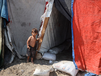 A displaced Palestinian child is standing in front of his family's tent near the beach in Deir al-Balah in the central Gaza Strip, on August...