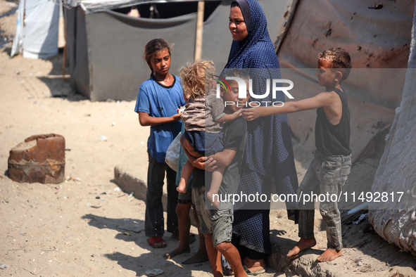 Displaced Palestinians are standing in front of their tent, which they are setting up near the beach in Deir al-Balah in the central Gaza St...