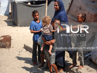 Displaced Palestinians are standing in front of their tent, which they are setting up near the beach in Deir al-Balah in the central Gaza St...