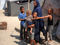 Displaced Palestinians are standing in front of their tent, which they are setting up near the beach in Deir al-Balah in the central Gaza St...