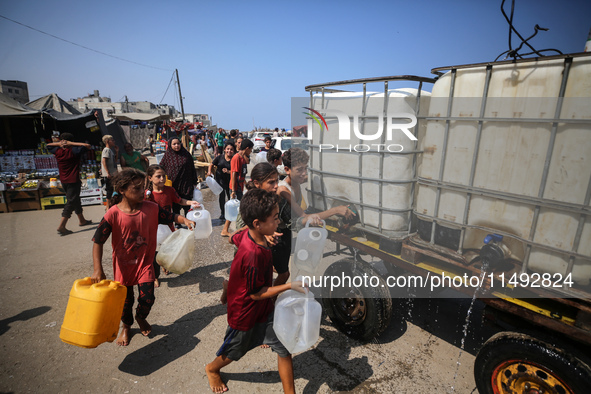 Palestinian displaced people are trying to fill containers with water in Deir el-Balah, Gaza Strip, on August 19, 2024, amid the ongoing con...