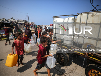 Palestinian displaced people are trying to fill containers with water in Deir el-Balah, Gaza Strip, on August 19, 2024, amid the ongoing con...