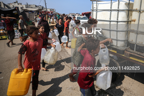 Palestinian displaced people are trying to fill containers with water in Deir el-Balah, Gaza Strip, on August 19, 2024, amid the ongoing con...