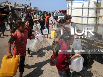 Palestinian displaced people are trying to fill containers with water in Deir el-Balah, Gaza Strip, on August 19, 2024, amid the ongoing con...