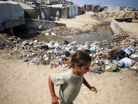 A displaced Palestinian girl is walking beside sewage water and a garbage dump in Deir al-Balah in central Gaza Strip on August 19, 2024, as...