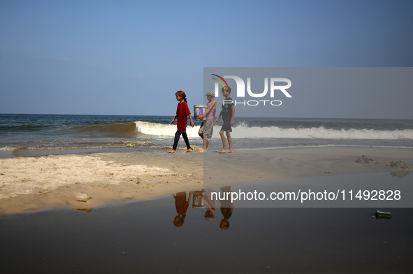 Palestinian displaced people are crossing a beach flooded with sewage water next to their tents in Deir al-Balah in central Gaza Strip, on A...