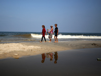 Palestinian displaced people are crossing a beach flooded with sewage water next to their tents in Deir al-Balah in central Gaza Strip, on A...