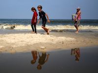 Palestinian displaced people are crossing a beach flooded with sewage water next to their tents in Deir al-Balah in central Gaza Strip, on A...