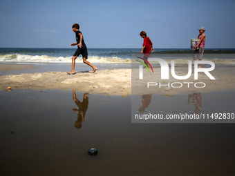 Palestinian displaced people are crossing a beach flooded with sewage water next to their tents in Deir al-Balah in central Gaza Strip, on A...