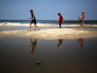 Palestinian displaced people are crossing a beach flooded with sewage water next to their tents in Deir al-Balah in central Gaza Strip, on A...