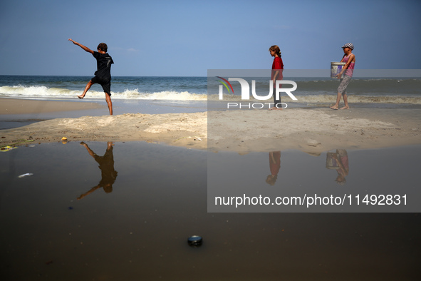 Palestinian displaced people are crossing a beach flooded with sewage water next to their tents in Deir al-Balah in central Gaza Strip, on A...