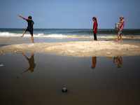 Palestinian displaced people are crossing a beach flooded with sewage water next to their tents in Deir al-Balah in central Gaza Strip, on A...