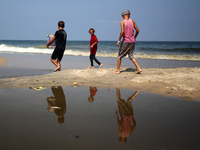 Palestinian displaced people are crossing a beach flooded with sewage water next to their tents in Deir al-Balah in central Gaza Strip, on A...