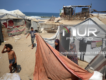 Displaced Palestinians are standing in front of their tent, which they are setting up near the beach in Deir al-Balah in the central Gaza St...