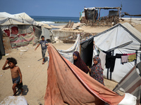 Displaced Palestinians are standing in front of their tent, which they are setting up near the beach in Deir al-Balah in the central Gaza St...