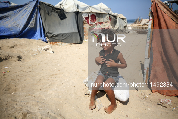 A displaced Palestinian girl is sitting beside the tents in Deir al-Balah in central Gaza Strip on August 19, 2024, amid the ongoing conflic...