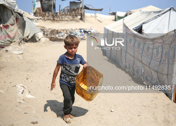 A displaced Palestinian child is walking beside sewage water and a garbage dump in Deir al-Balah in central Gaza Strip on August 19, 2024, a...