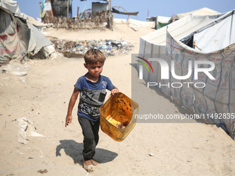 A displaced Palestinian child is walking beside sewage water and a garbage dump in Deir al-Balah in central Gaza Strip on August 19, 2024, a...