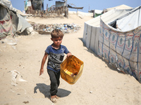 A displaced Palestinian child is walking beside sewage water and a garbage dump in Deir al-Balah in central Gaza Strip on August 19, 2024, a...