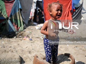 A Palestinian girl is suffering from a skin rash and is walking past a pool of sewage water on a street in Deir al-Balah in central Gaza Str...