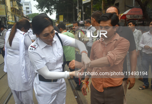 A Kolkata policewoman officer is tying a Rakhi, or a traditional Indian sacred thread, on the wrist of a doctor at a protest rally for the R...