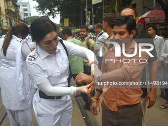 A Kolkata policewoman officer is tying a Rakhi, or a traditional Indian sacred thread, on the wrist of a doctor at a protest rally for the R...