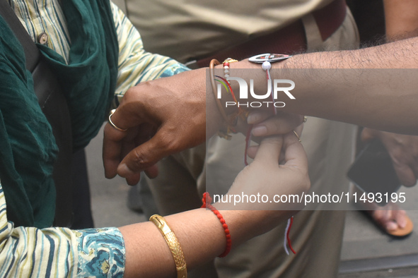 A doctor is tying Rakhis, or a traditional Indian sacred thread, on the wrist of a Kolkata Police officer during a protest rally for the R G...