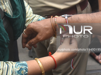 A doctor is tying Rakhis, or a traditional Indian sacred thread, on the wrist of a Kolkata Police officer during a protest rally for the R G...